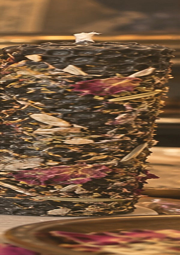 Concept photograph of ivory rolled beeswax candle with botanicals