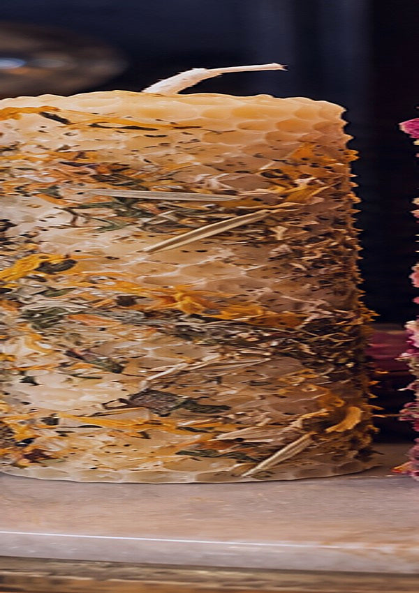 Concept photograph of midnight indigo rolled beeswax candle with botanicals