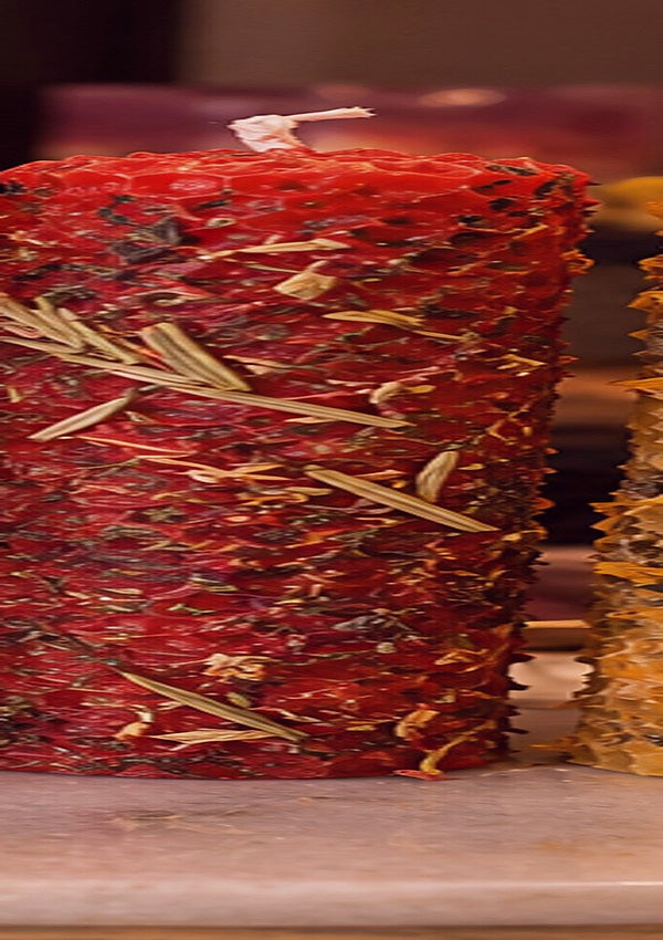 Concept photograph of burgundy plum rolled beeswax candle with botanicals
